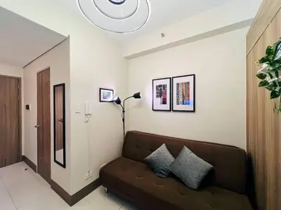 a living room with a couch and a lamp at 1BR Condotel with Balcony at FAME Residences #FM25 in Manila