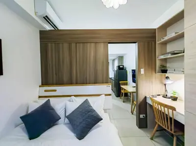 a bedroom with a bed and a desk and a kitchen at 1BR Condotel with Balcony at FAME Residences #FM08 in Manila