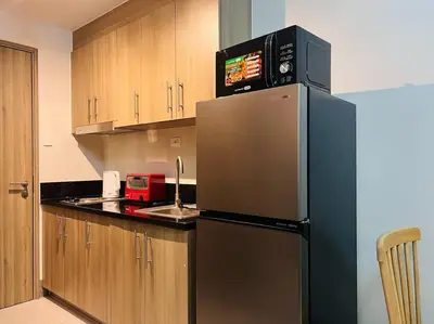 a kitchen with a stainless steel refrigerator with a microwave at 1BR Condotel with Balcony at FAME Residences #FM28 in Manila
