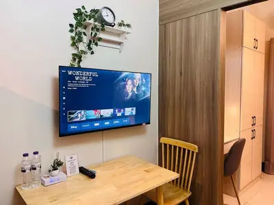 a room with a table and a tv on the wall at 1BR Condotel with Balcony at FAME Residences #FM28 in Manila