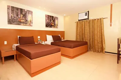 a hotel room with two beds and a tv at Eurotel Las Pinas in Manila