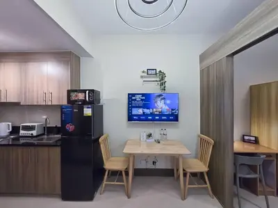 a kitchen with a table with chairs and a refrigerator at 1BR Condotel with Balcony at FAME Residences #FM30 in Manila