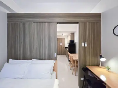 a bedroom with a bed and a desk and a dining room at 1BR Condotel with Balcony at FAME Residences #FM32 in Manila
