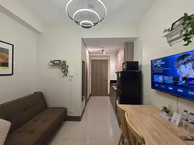 a living room with a couch and a large screen tv at 1BR Condotel with Balcony at FAME Residences #FM33 in Manila