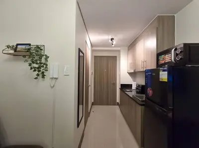 a kitchen with a black refrigerator and wooden cabinets at 1BR Condotel with Balcony at FAME Residences #FM33 in Manila