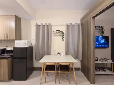 a kitchen with a table and a black refrigerator at 1BR Condotel with Balcony at FAME Residences #FM34 in Manila
