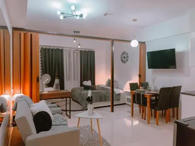 a living room with a couch and a dining room at Bright & Airy Studio near Venice Mall with Pool, Gym & Fast WiFi in Manila