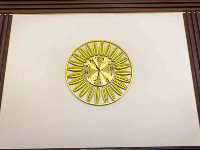 a gold clock hanging on a white wall at 1BR Makati, Air Residences M002 in Manila