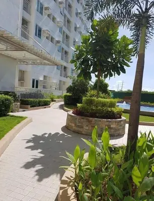 a large apartment building with a palm tree and a sidewalk at Staycation One bedroom in Manila