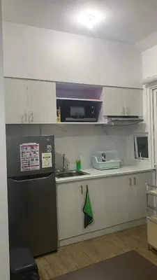a kitchen with white cabinets and a black refrigerator at Staycation One bedroom in Manila