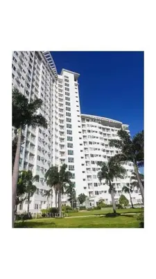 a large white building with palm trees in front of it at Staycation One bedroom in Manila
