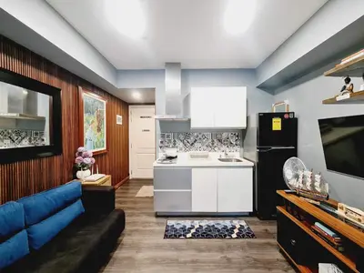 a living room with a blue couch and a kitchen at Azure Paranaque near Airport in Manila