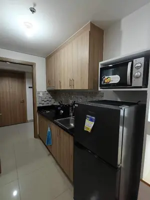 a kitchen with a black refrigerator and a microwave at The SK home at the shore in Manila