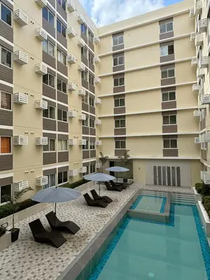 a swimming pool in front of a building with umbrellas at Condo in silang - near nuvali and tagaytay in Silang