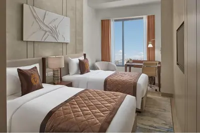 a hotel room with two beds and a desk at Grand Westside Manila Bay in Manila