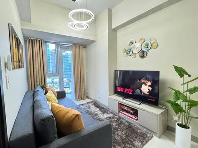 a living room with a couch and a flat screen tv at Executive Gem beside Malls and Bars at Uptown BGC in Manila