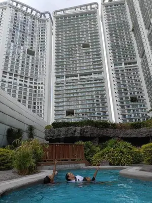 a person in a swimming pool with two tall buildings at Skyloft Acqua Private Residences in Manila
