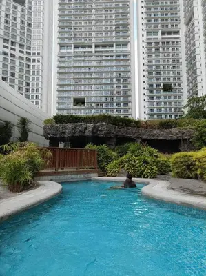 a person sitting in a swimming pool with tall buildings at Skyloft Acqua Private Residences in Manila