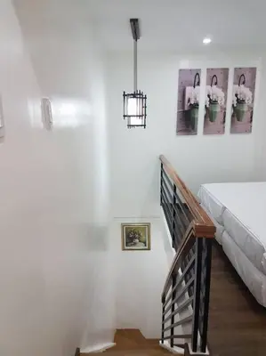 a white bedroom with a bed and a staircase at Loft Style Condo Unit in Makati with Netflix WIFI in Manila