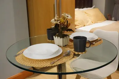 a glass table with plates and cups on top of it at Quiet Condo with Fast WiFi, Own Balcony, Pool and Gym in Manila