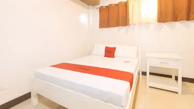 a small white room with a bed and a night stand at RedDoorz at MGP Apartelle Near Espana in Manila