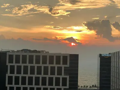 a sunset over the ocean and two tall buildings at 1 BR Condo with Balcony in Manila