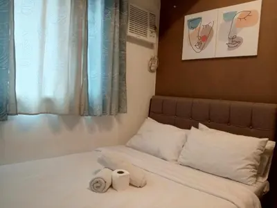 a bed with two rolls of towels sitting on it at Grand Riviera suite Condotel Near SLEC in Manila