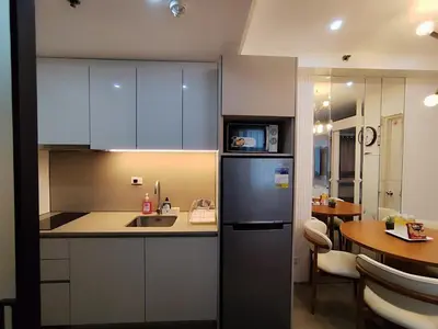 a kitchen with a sink and a refrigerator and a table at Aya's Place Two Bedrooms near MOA in Manila