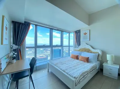 a bedroom with a bed and a desk and windows at BGC Skyline 2BR Suite with Parking in Uptown BGC in Manila