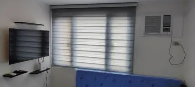 a window with blinds in a room with a tv at Grand Riviera Suites in Manila