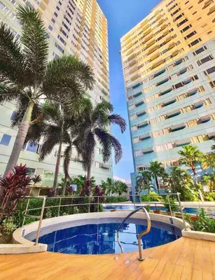 a swimming pool with palm trees and tall buildings at Cozy & Affordable Stay Near Bgc #rt33005 in Manila