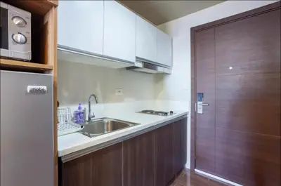 a small kitchen with a sink and a refrigerator at COZY SKYLINE CONDO in MAKATI in Manila