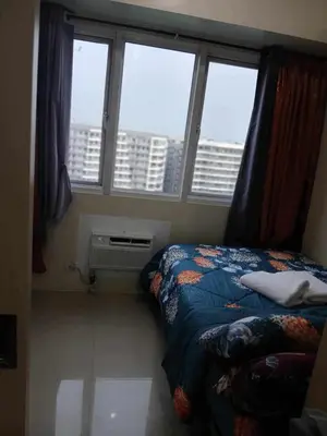a bedroom with a bed and a window with a view at BLUE sea Residences in Manila