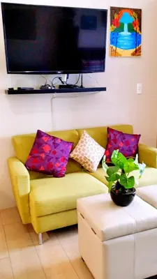 a living room with a yellow couch with colorful pillows at Eastwood Legrand Tower 3 condominium in Manila