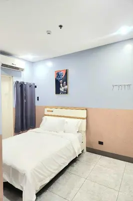 a bedroom with a large bed with white sheets at Qingqing Hotel Pasay Manila near MOA in Manila