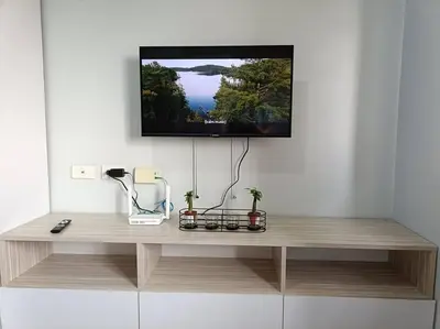 a tv hanging on a wall above a wooden table at Lorde's Hideaway in Manila