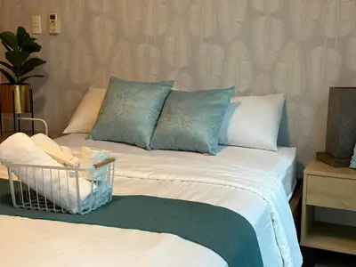 a bed with pillows and a basket on top of it at BGC One Uptown Suite by Christine Suites PH in Manila