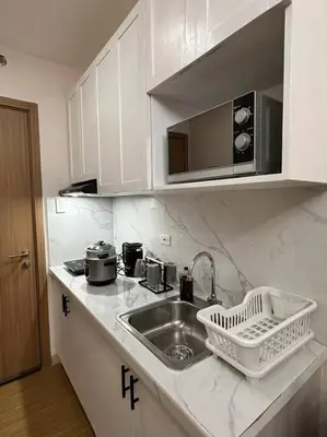 a white kitchen with a sink and a microwave at Cozy Condo in Taguig in Manila