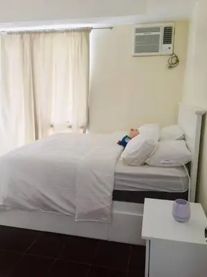a bedroom with a white bed with a window at Lovely two bedroom apartment with balconies in Manila