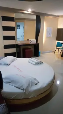 a bedroom with a bed with a desk and a mirror at Bermuda Hotel in Manila
