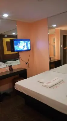 a room with a bed and a tv on a wall at Bermuda Hotel in Manila