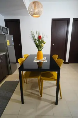 a black table with yellow chairs and a vase with flowers at Hayahay Rentals in Manila