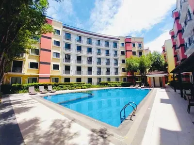 a hotel with a swimming pool in front of a building at Belthena Suite in Las Piñas Near Airport in Manila