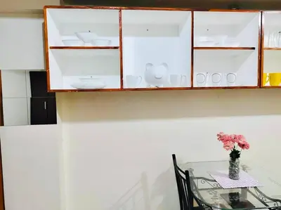 a glass table with a vase of flowers and a cabinet at Belthena Suite in Las Piñas Near Airport in Manila