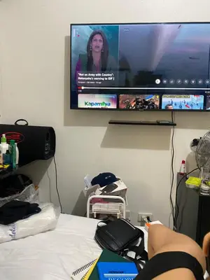 a person laying on a bed in front of a tv at Pierrecondotel in Manila