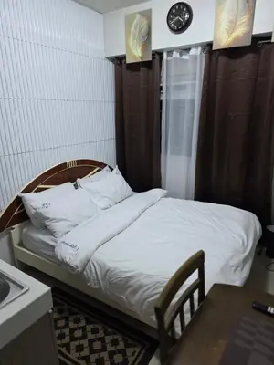 a bed in a room with a clock on the wall at Nicecondote in Manila