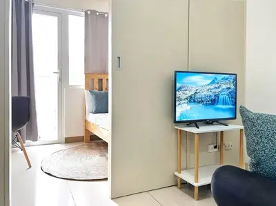 a living room with a television on a table at 1-Bedroom Condo in Las Piñas in SM SouthMall in Manila