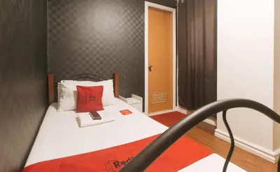 a small bedroom with a bed with a red pillow at RedDoorz at Emperor Manila Boutique Hotel in Manila