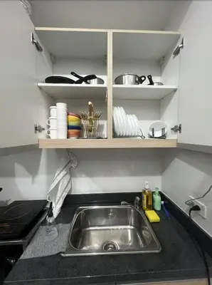 a kitchen counter with a sink and shelves at POEA Mega Mall WiFi Netflix in Manila