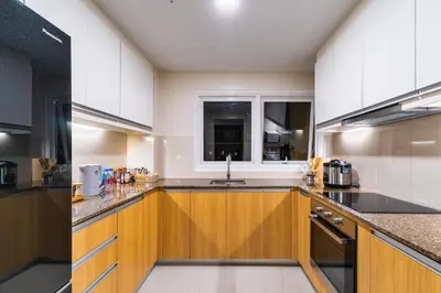a kitchen with wooden cabinets and a window at Ocean View Condo with Infinity Pool, Gym, Spa - Next to Okada, Solaire & MOA in Manila